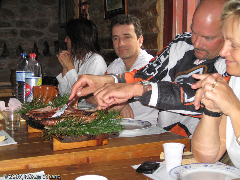 Finally, the food arrives. John cuts the sausages.